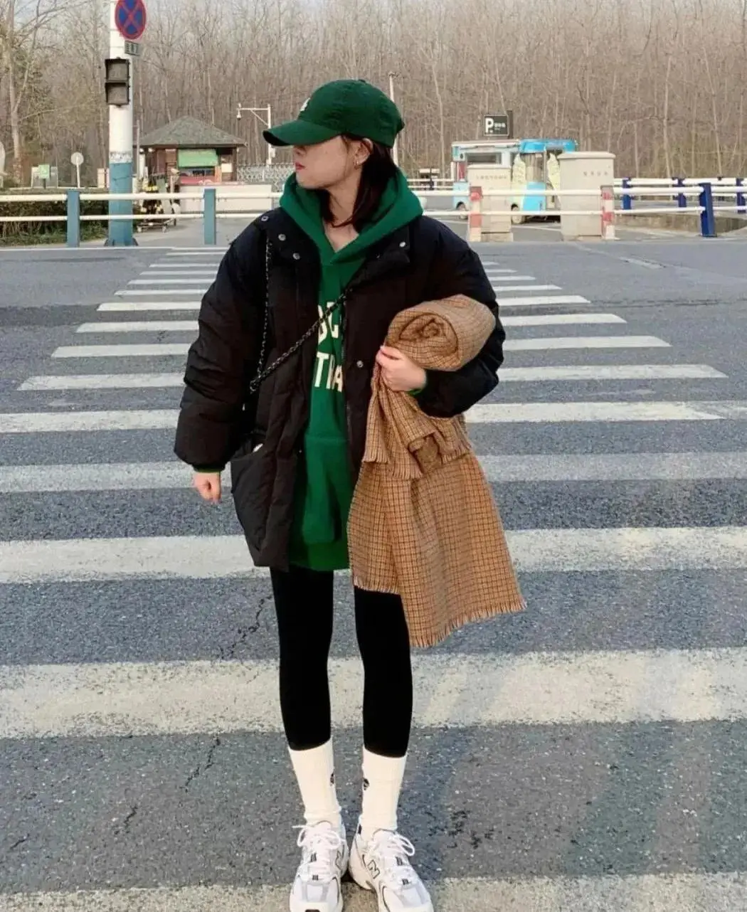 Mặc áo phao đen và quần legging giúp bạn trông cao và thon thả hơn, chiếc áo hoodie xanh lá cây bên trong làm nổi bật toàn bộ trang phục khiến nó trở nên thời trang. Tất trắng và giày thể thao màu trắng giản dị và hợp thời trang, khiến sự kết hợp trở nên thú vị hơn.